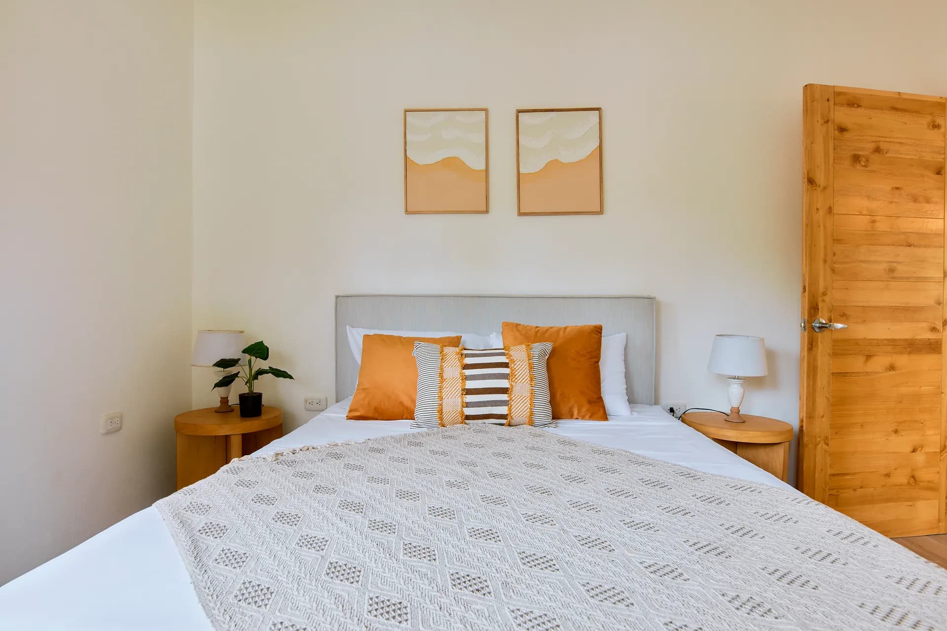 Cama queen de Casa Gray con almohadas decorativas anaranjadas