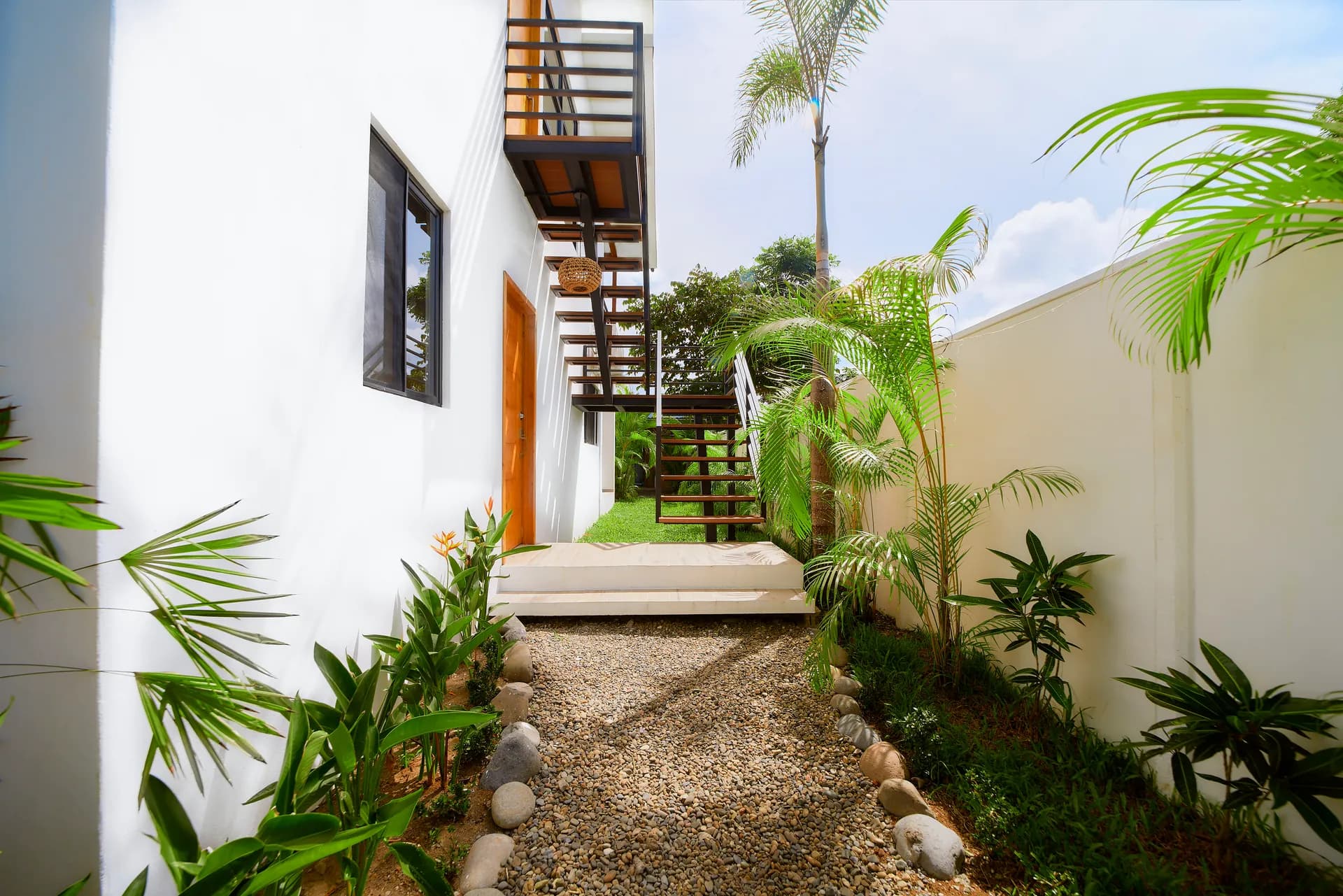 Pasillo de entrada de Casa Gray con cama de día y escaleras al apartamento superior
