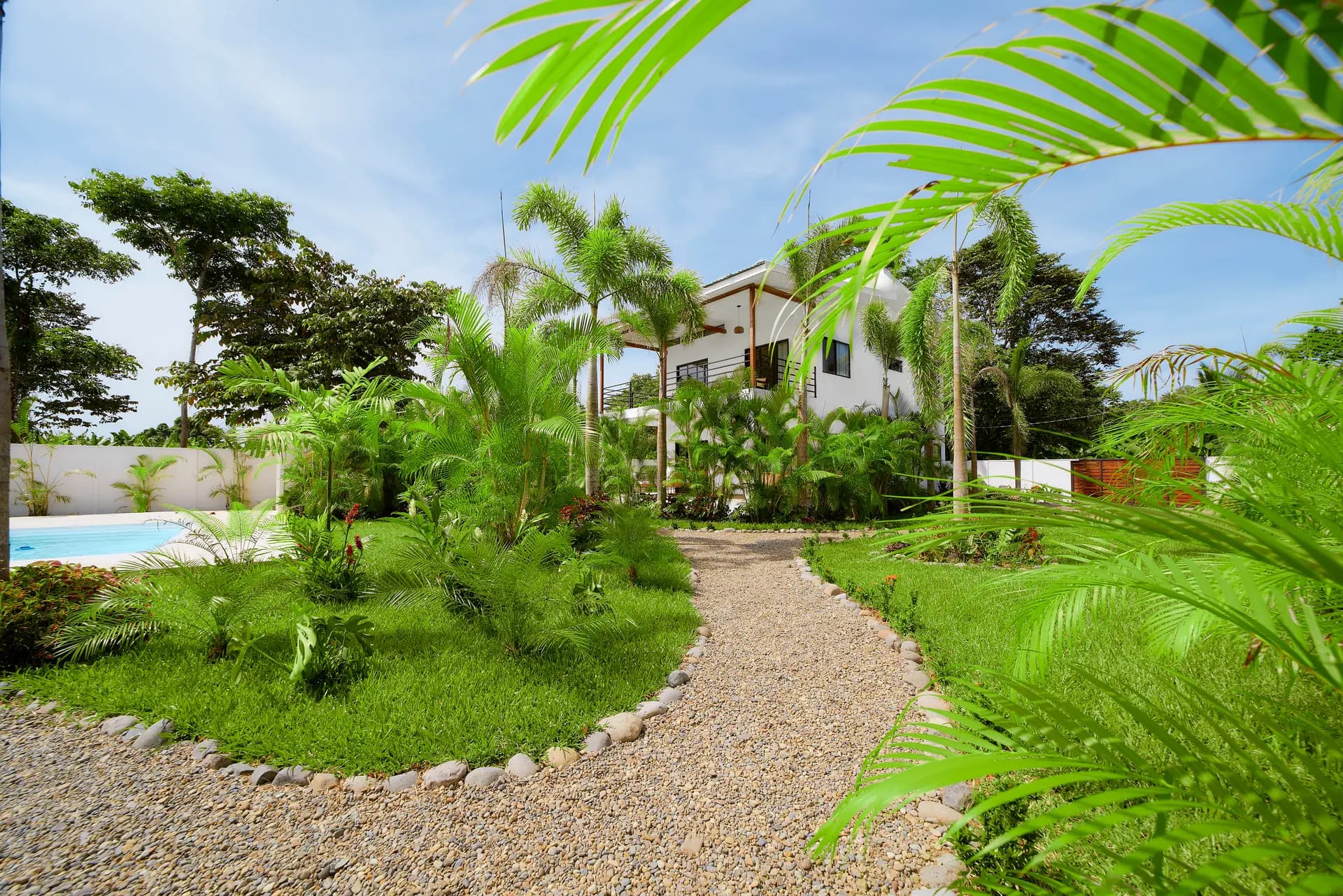 Exterior de la casa de dos pisos de Casa Gray rodeada de palmeras