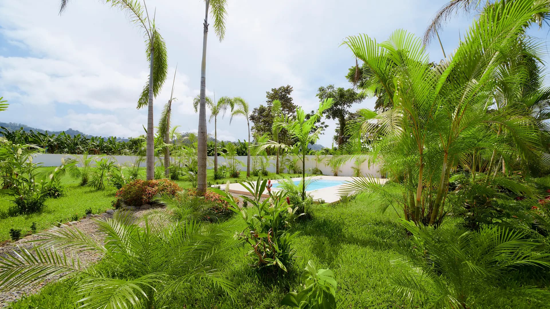 Jardín tropical de Casa Gray con la piscina y montañas al fondo